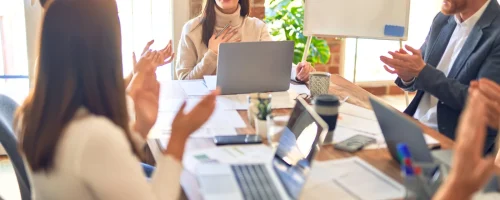 groupe-d-employes-souriants-heureux-et-confiants-travaillant-avec-le-sourire-sur-le-visage-applaudissant-l-un-d-eux-au-bureau-scaled